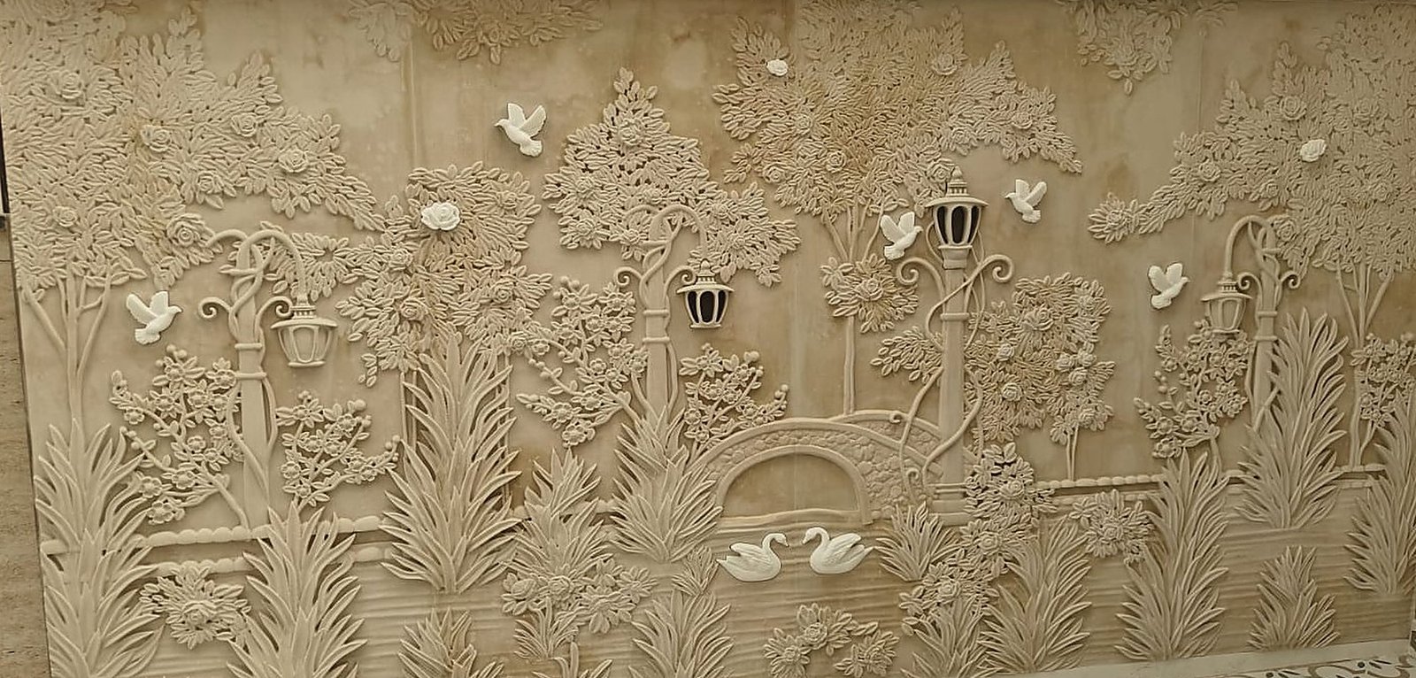 Carved stone garden mural with trees, lanterns, birds and swans